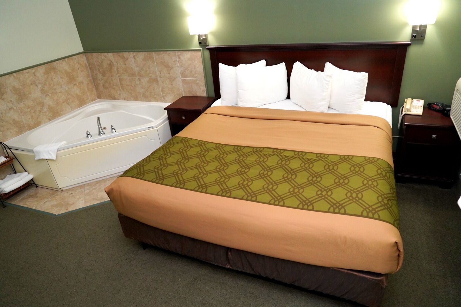 A hotel room with a large bed, a separate bathtub, and two bedside tables with lamps.