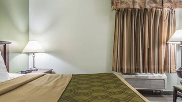 Una camera d'albergo con un letto, lampade sui comodini, un termosifone e tende.