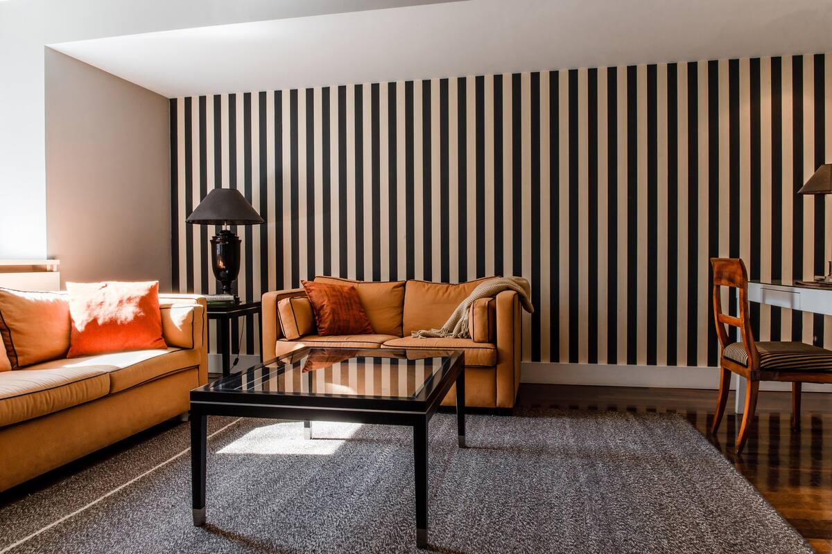 Una sala de estar con una pared a rayas, un sofá, una mesa de centro y una lámpara.