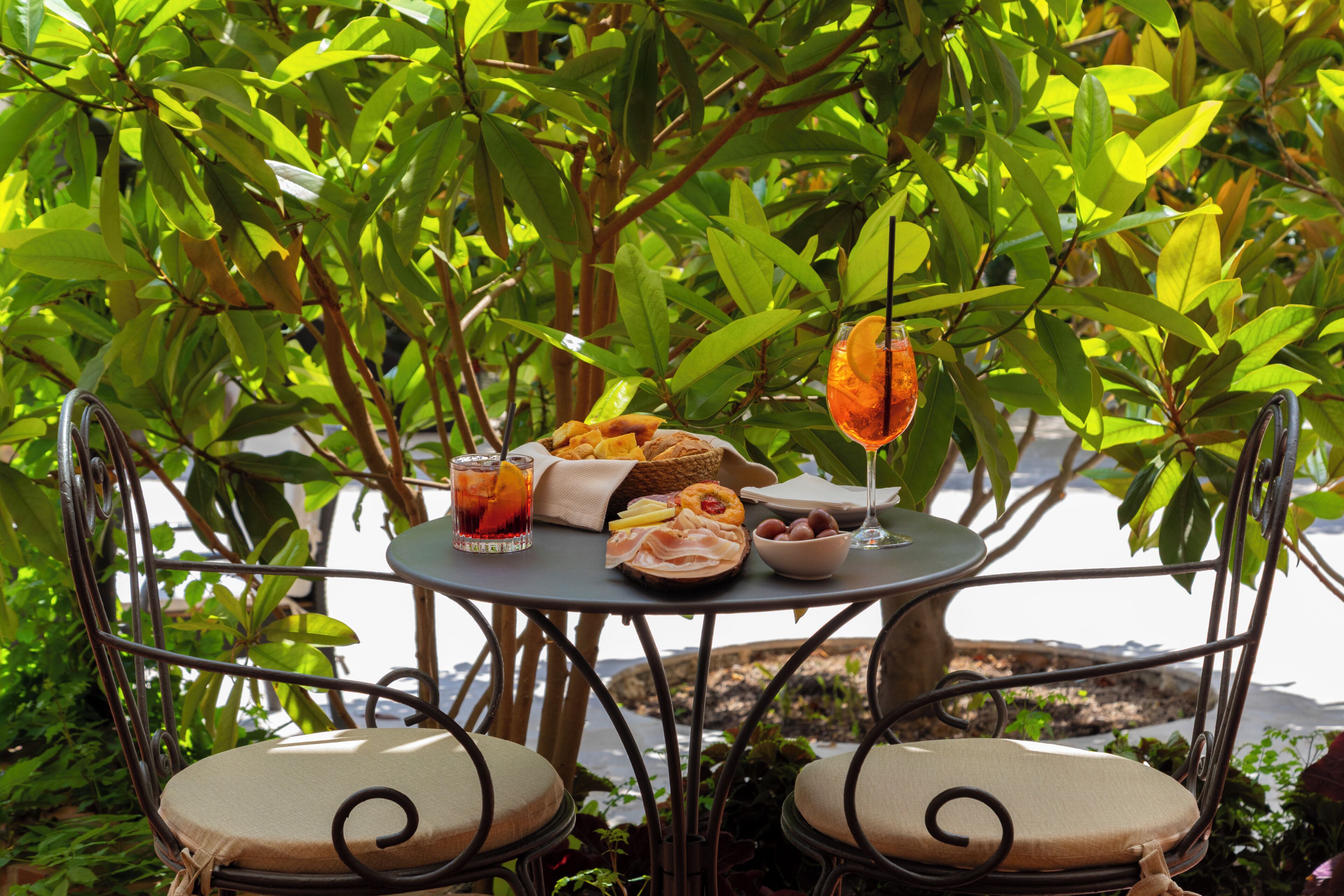 A table set outdoors with a variety of food items, a drink, and a glass with a lemon slice.