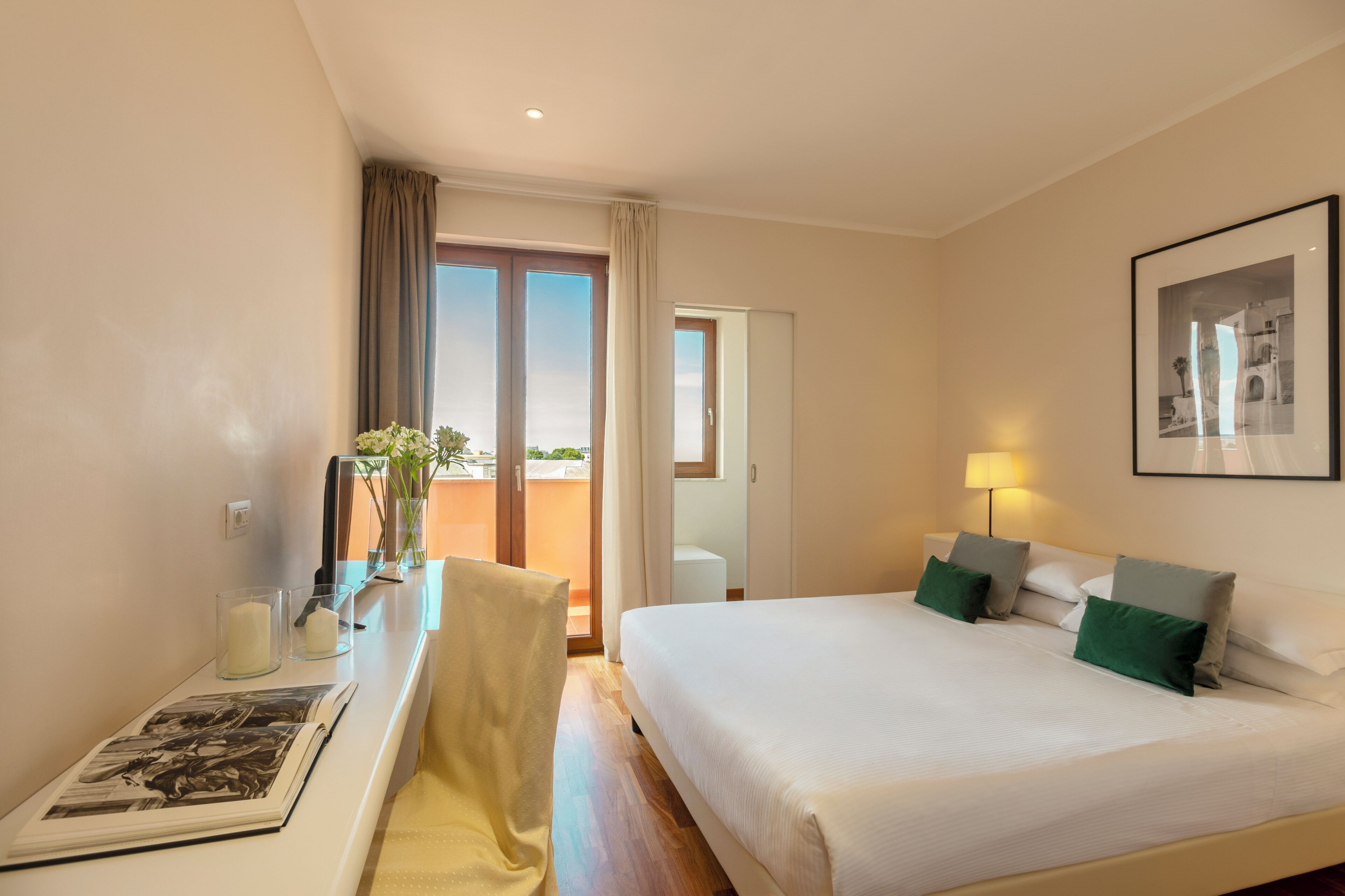 Habitación de hotel con cama, mesita de noche, lámpara y un cuadro en la pared.