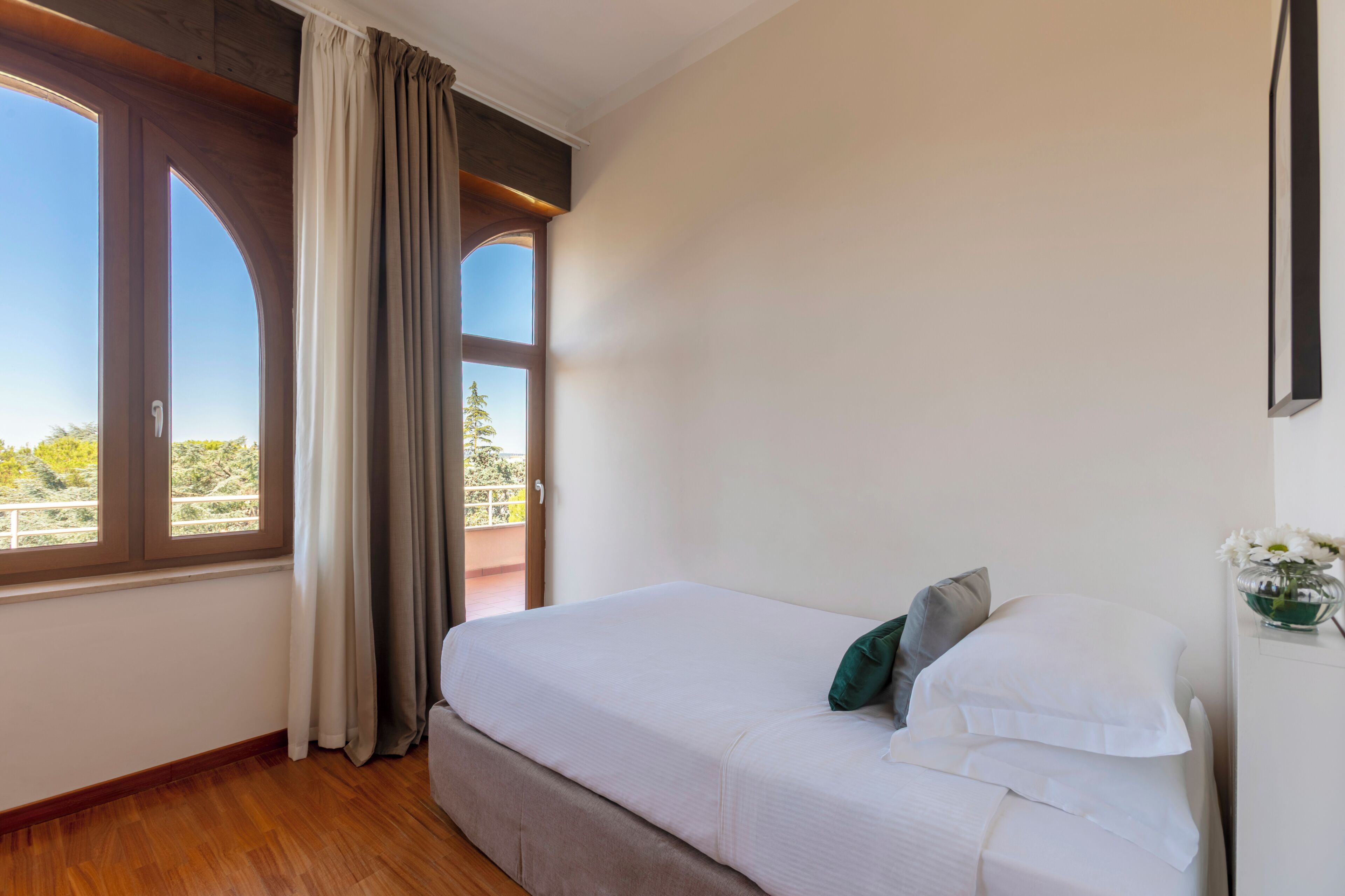 Un dormitorio con cama, ventana y vista a zonas verdes.