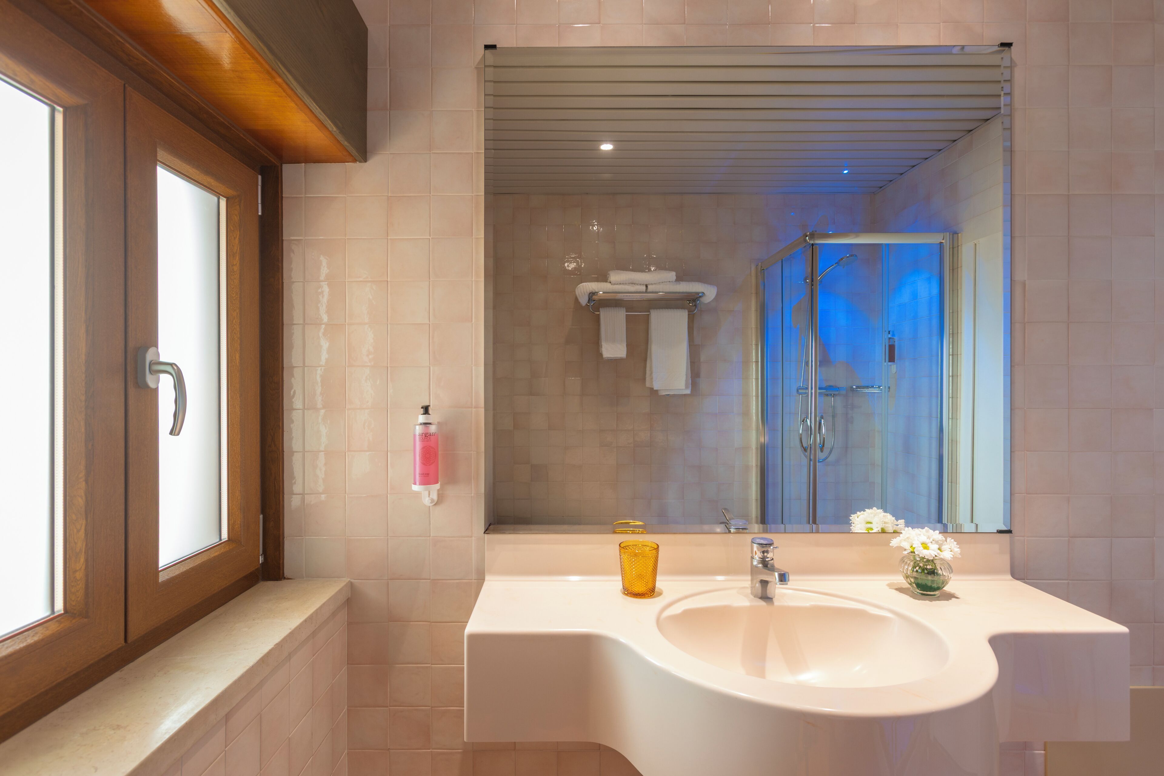 Une salle de bain moderne avec un grand miroir, un lavabo et un espace douche.