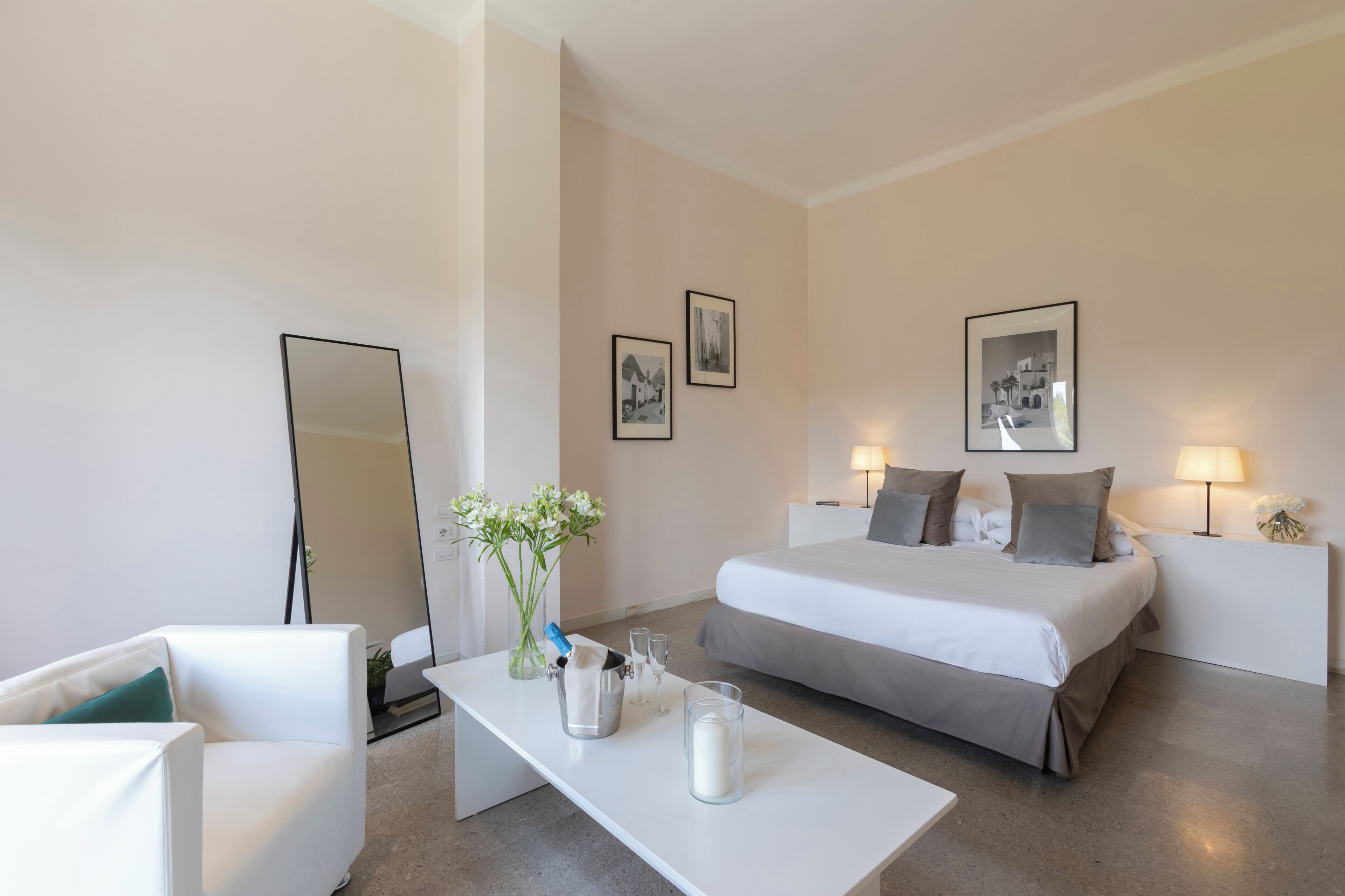 A hotel room with a bed, bedside tables, a chair, a desk, and a mirror.