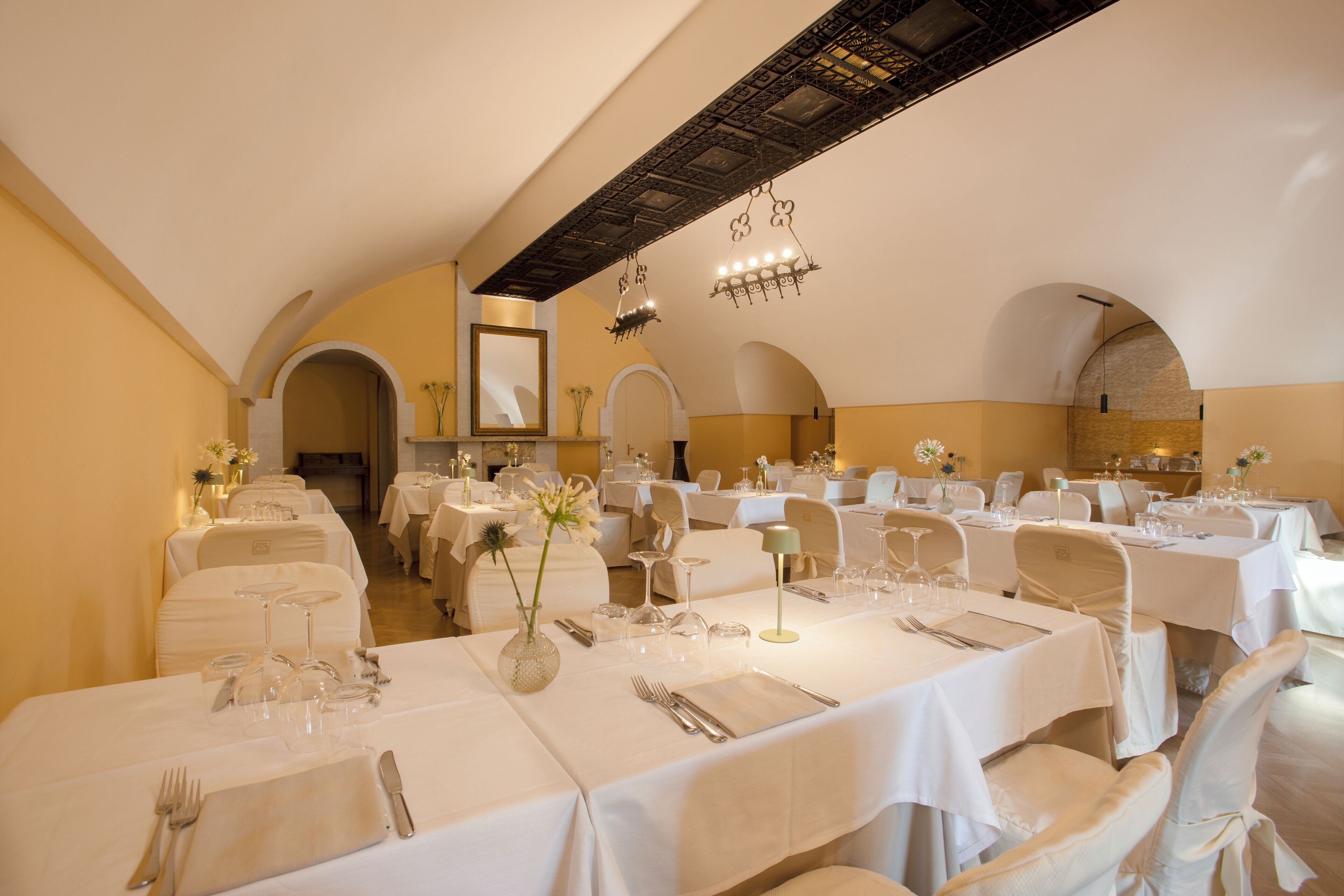 Een restaurant met meerdere gedekte tafels, witte tafelkleden en elegante servies.