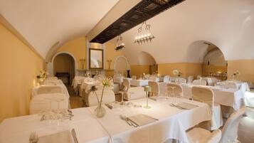 Een restaurant met meerdere gedekte tafels, witte tafelkleden en elegante servies.