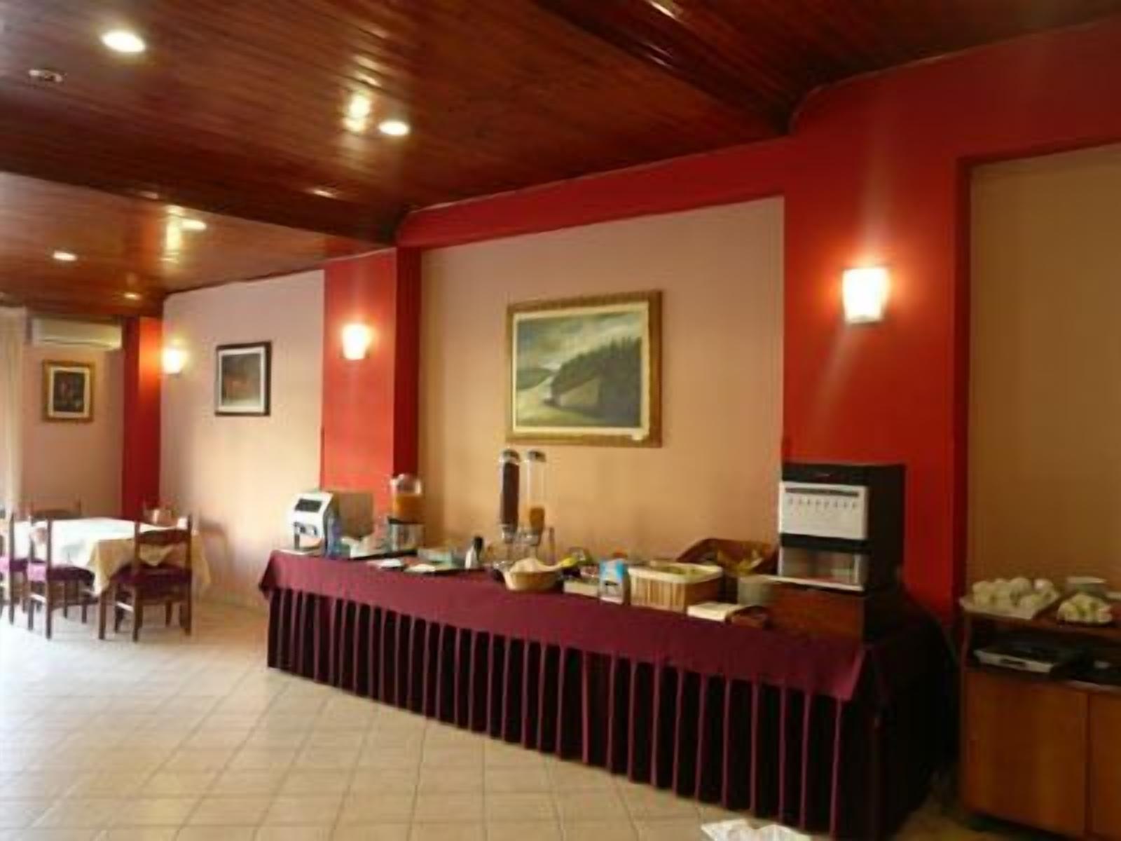 A hotel lobby with a reception desk, chairs, and a wall-mounted painting.