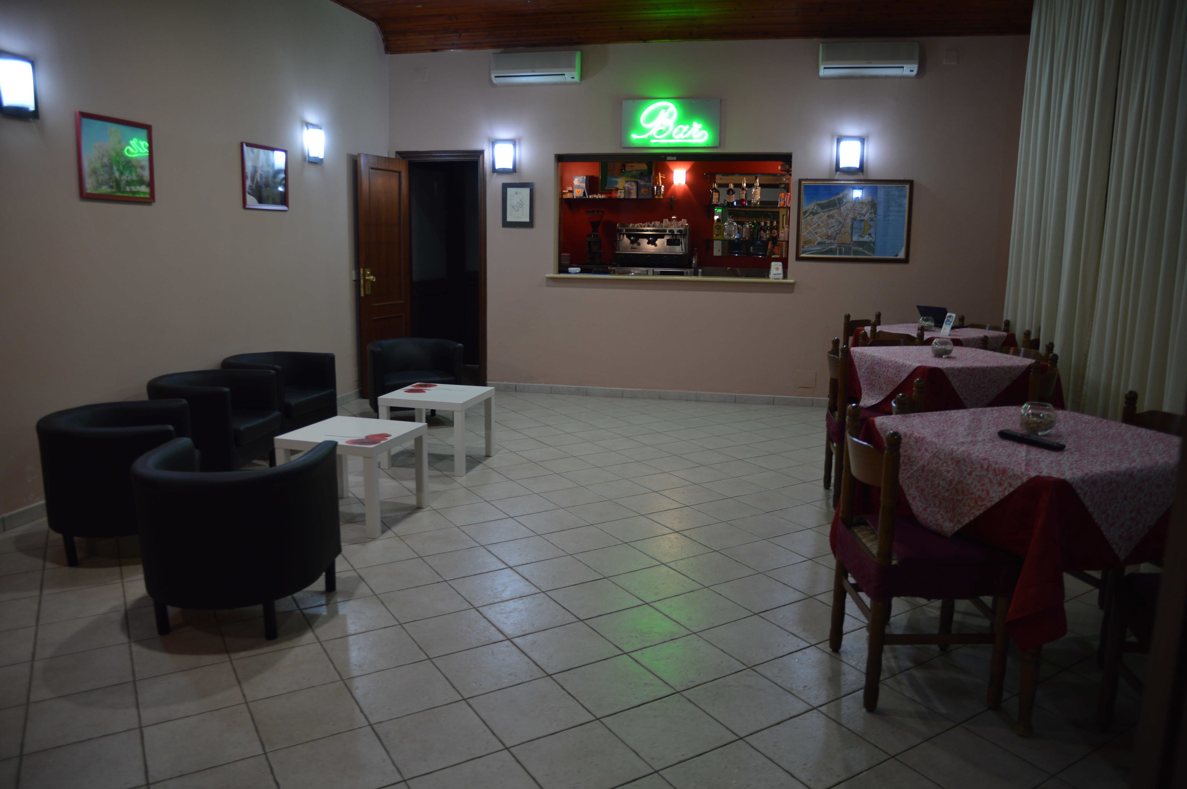 A restaurant with a bar area, tables, and chairs.