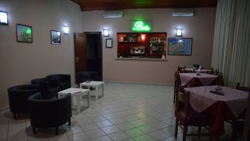 A restaurant with a bar area, tables, and chairs.