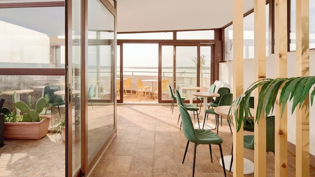 A spacious patio area with a view of the city skyline, featuring modern furniture and potted plants. - Hotel Centrale (Syracuse)