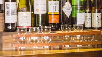 Diversas garrafas de vinho e copos em uma prateleira de madeira.