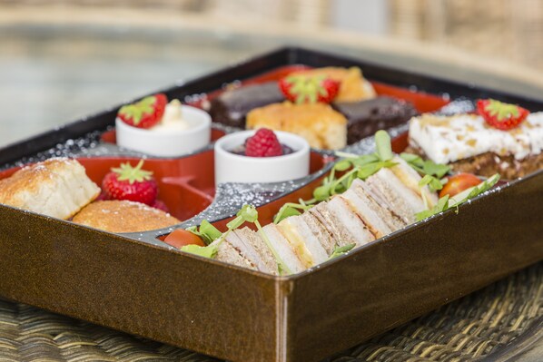 A rectangular serving tray with various food items including sliced bread, strawberries, and a dessert with a berry topping.