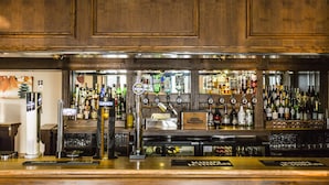 A bar with a wooden panel design, various liquor bottles, and a beer tap. - Stanton House Hotel (Swindon)