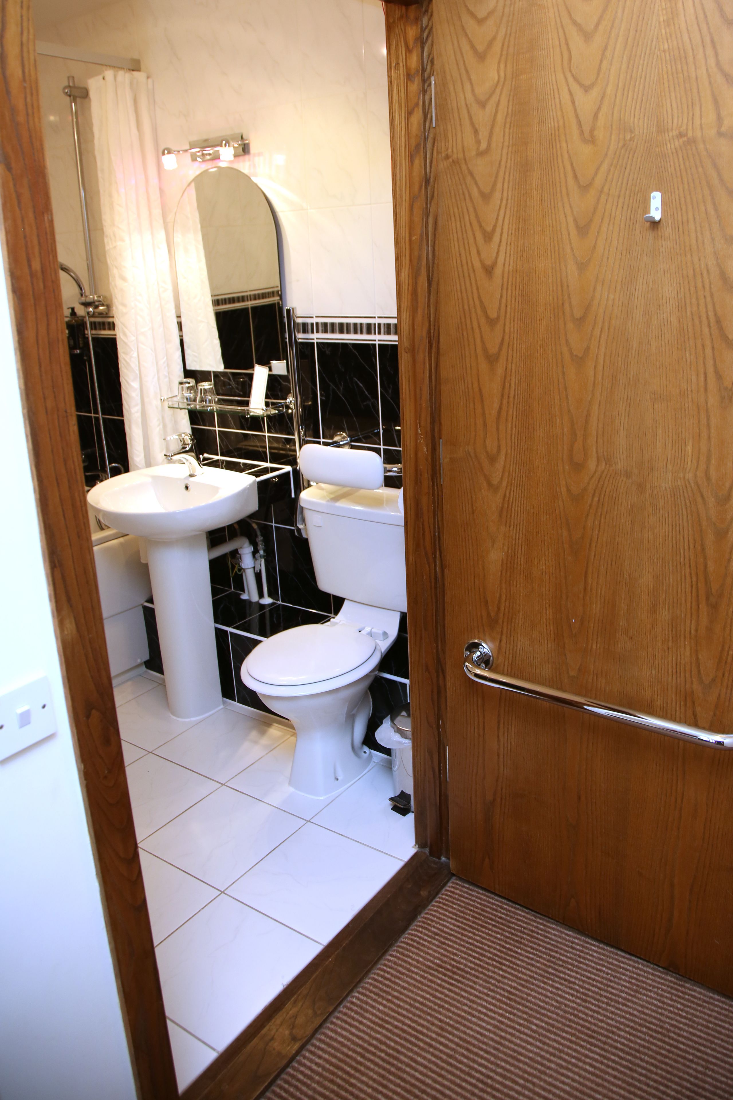 Un baño con lavamanos, inodoro y ducha blancos.