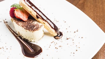 Un dessert con glassa al cioccolato, una fragola e una foglia di menta su un piatto bianco.