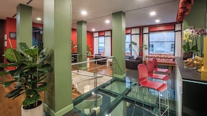 A hotel lobby with a glass staircase, red chairs, and green pillars. - Mercure Roma Centro St. John (Rome)
