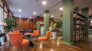 A modern interior with wooden flooring, orange chairs, a marble table, and green walls. - Mercure Roma Centro St. John (Rome)