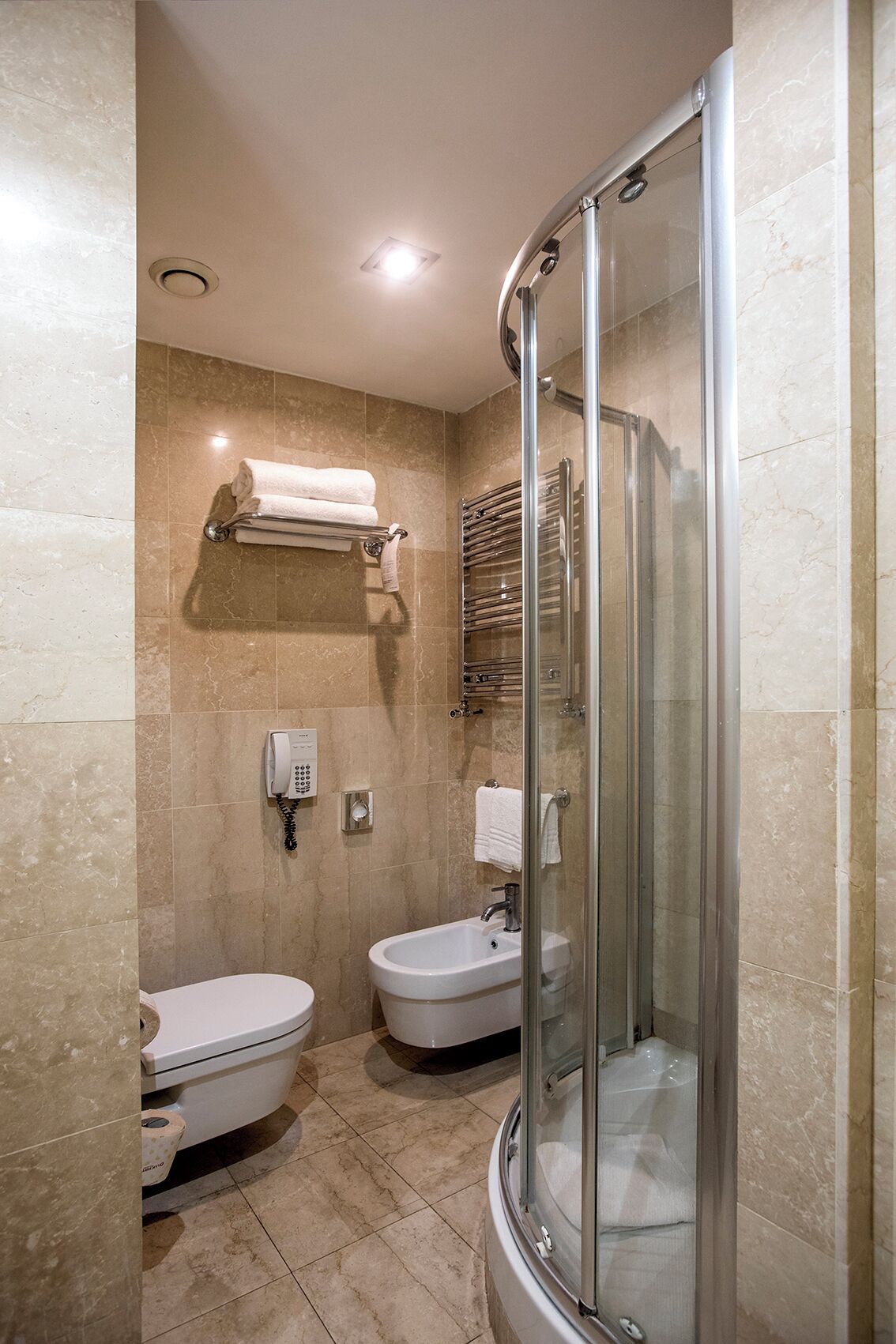 A modern bathroom with a glass-enclosed shower, two sinks, and a toilet.