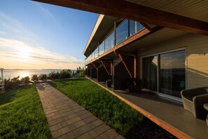 A modern house with a balcony overlooking a grassy area and a body of water. - Auberge De La Pointe (Rivière-du-Loup)