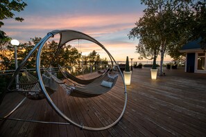 A hammock chair on a wooden deck with a sunset view. - Auberge De La Pointe (Rivière-du-Loup)