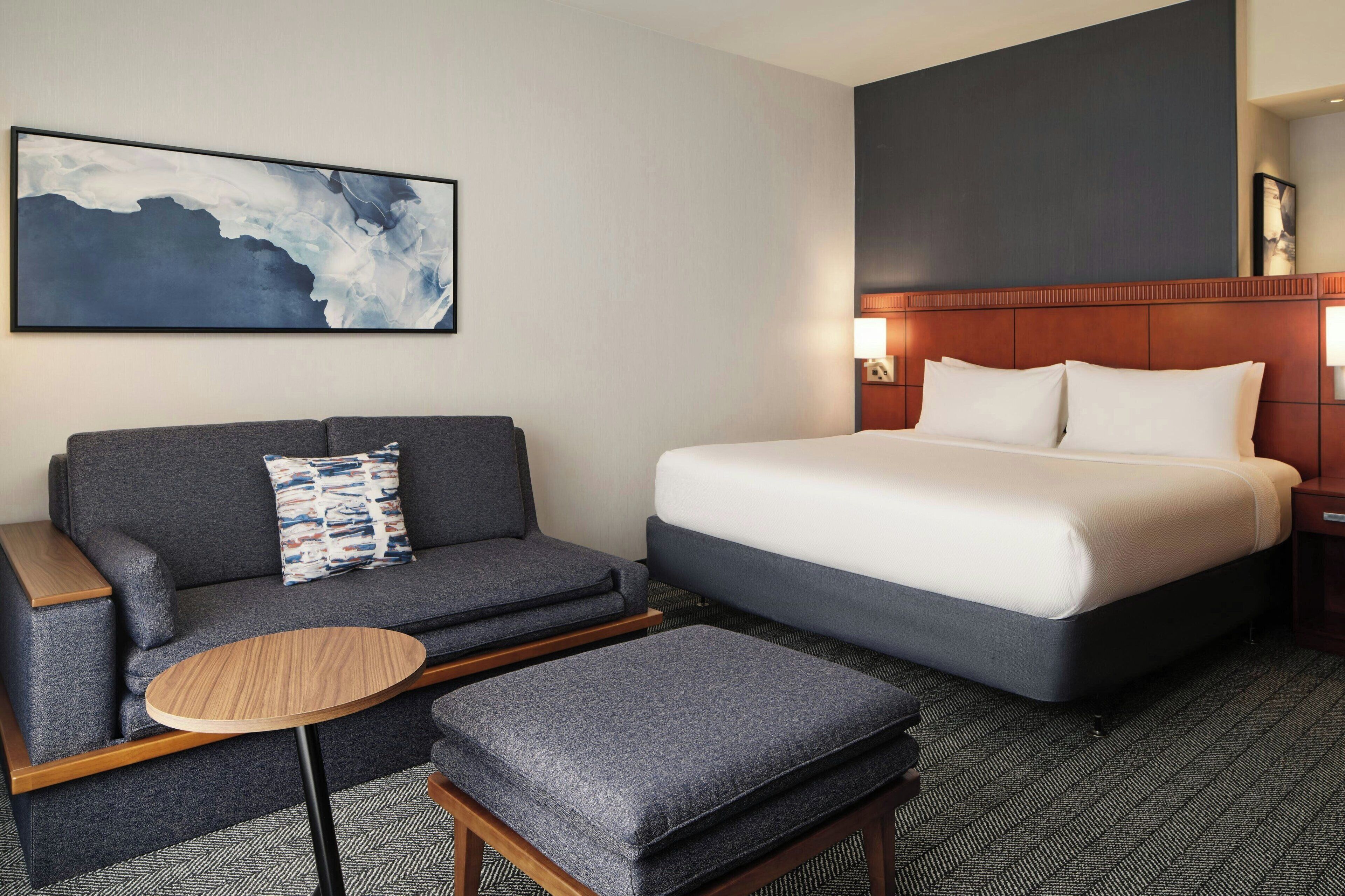 Ein Hotelzimmer mit einem Bett, einem Sofa, einem kleinen Tisch und einem Wandbild.