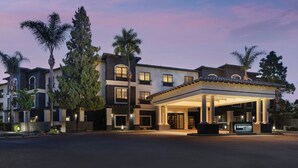 Un hotel de varios pisos con un patio cubierto, palmeras y un letrero que dice 'Courtyard by Marriott'.