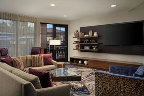 Una sala de estar moderna con un sofá, sillones, una mesa de centro y un televisor de pantalla plana montado en la pared.