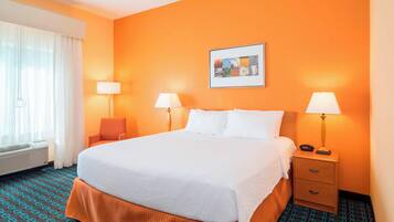 A hotel room with a large bed, two bedside tables with lamps, a framed picture on the wall, and a window with curtains.