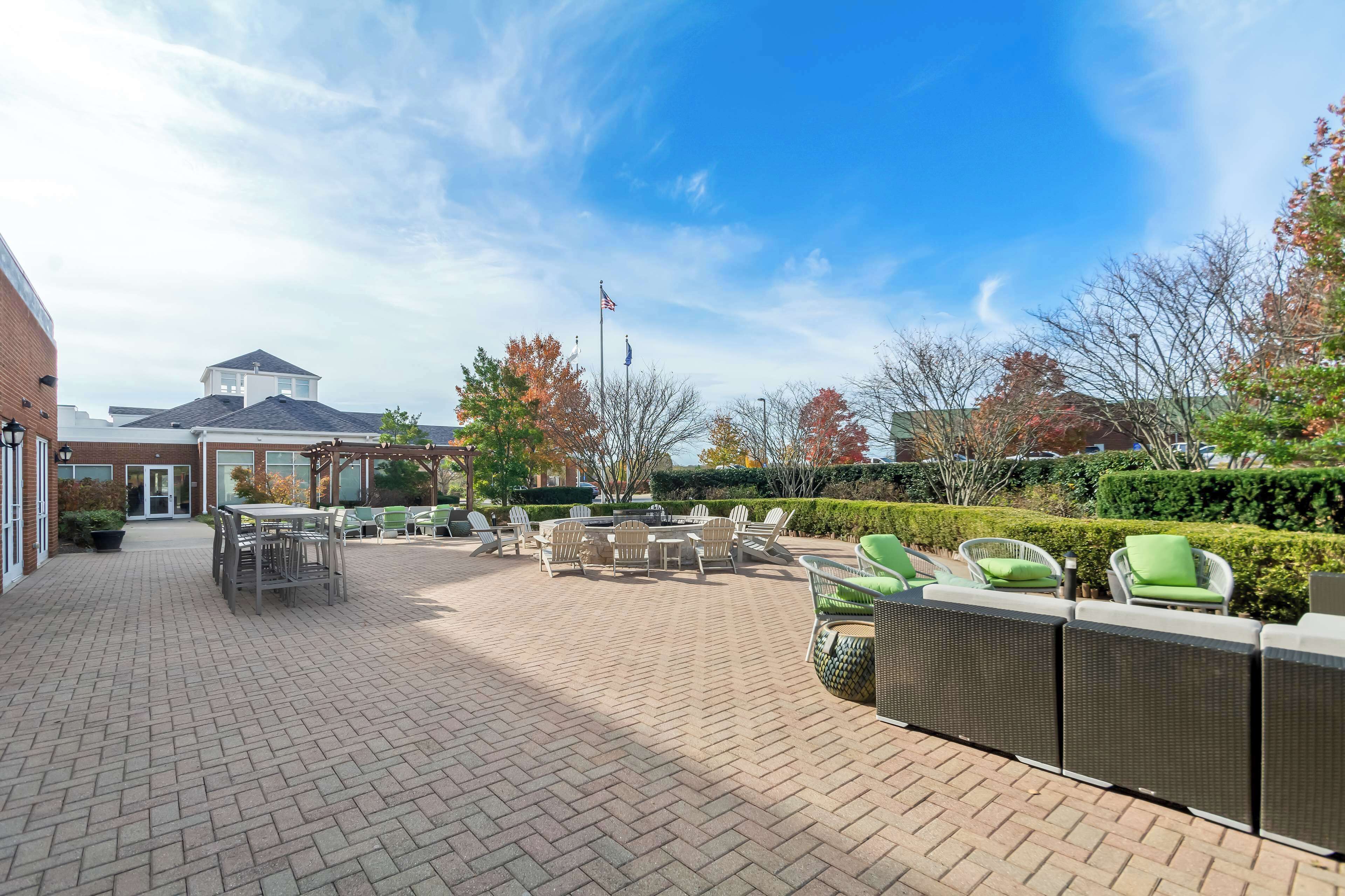 An outdoor patio area with a brick floor, outdoor seating with chairs and tables, and a flagpole with an American flag.
