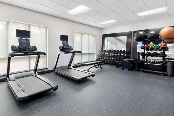 A gym with treadmills, dumbbells, and exercise balls.
