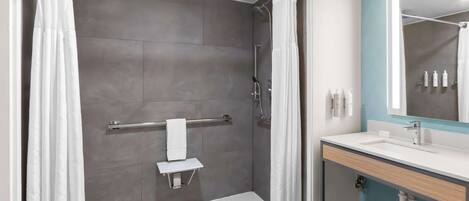 A modern bathroom with a shower, a towel rack, a sink, and a mirror.