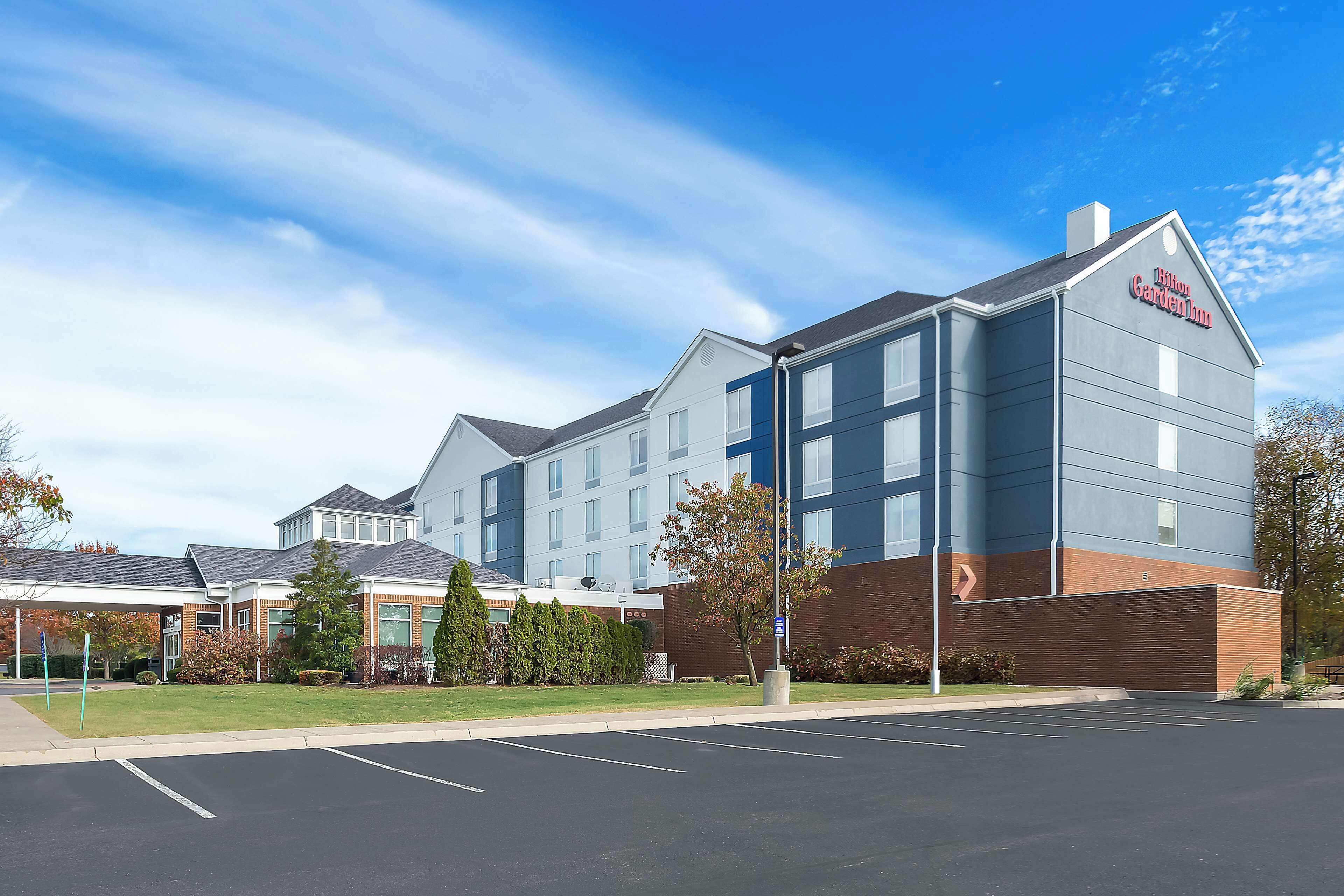 A hotel with a modern design, featuring a prominent sign, a parking lot, and a well-maintained lawn.