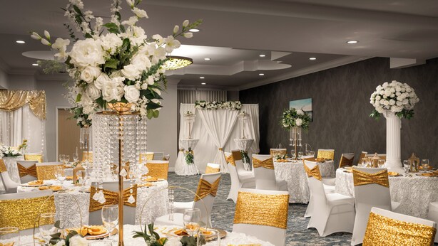 A banquet hall with round tables, white and gold decor, and floral arrangements. - Fairfield Inn & Suites by Marriott Jacksonville Butler Blvd (Jacksonville)