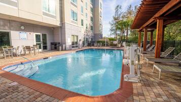 A swimming pool with a 3 ft depth marker, surrounded by lounge chairs and a covered area with wooden beams.