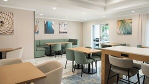 A modern dining area with green upholstered seating, wooden tables, and artwork on the walls. - Fairfield Inn & Suites by Marriott Jacksonville Butler Blvd (Jacksonville)