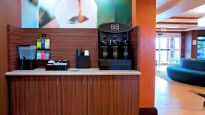A reception area with a coffee machine, a digital display, and a wall-mounted sign. - Fairfield Inn & Suites by Marriott Ames (Ames)
