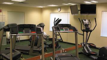 A fitness center with treadmills, elliptical machines, and a mirrored wall.