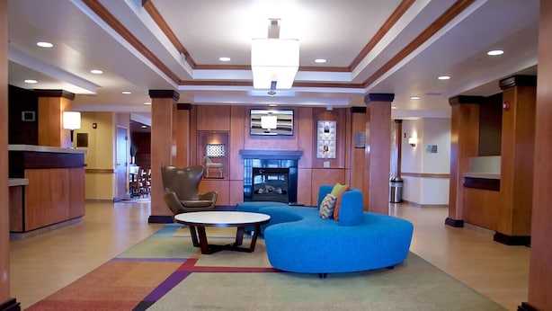 A lobby with a blue sofa, a round table, and a leather chair. - Fairfield Inn & Suites by Marriott Ames (Ames)