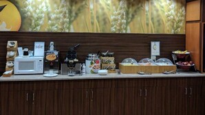 A breakfast buffet area with a microwave, hot beverages, and various food items. - Fairfield Inn & Suites by Marriott Ames (Ames)