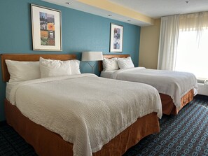 A hotel room with two beds, a headboard, a lamp, and framed pictures on the wall. - Fairfield Inn & Suites by Marriott Ames (Ames)