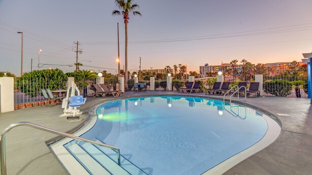 A swimming pool with lounge chairs and a lifeguard stand. - Emerald Coast Inn And Suites (Fort Walton Beach)