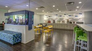 A modern kitchen with a central island, bar seating, and a fish tank. - Emerald Coast Inn And Suites (Fort Walton Beach)