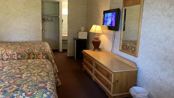 A hotel room with two beds, a television, a dresser, a lamp, and a mirror.