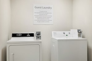 A guest laundry area with two Whirlpool washers, a sign with laundry instructions, and a wall-mounted dryer.