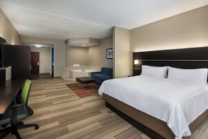 Una habitación de hotel con una cama grande, un escritorio, una silla, un sofá y un baño a la vista.