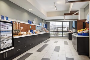 Una cocina moderna con barra desayunadora, exhibición de yogur, huevos y leche, y un amplio ventanal con vistas al exterior.