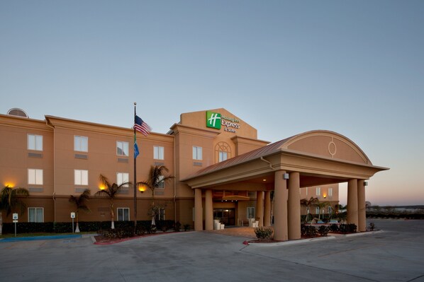 Welcome to the Holiday Inn Express & Suites, featuring a covered entrance with a waiting area and a symmetrical facade with multiple windows.