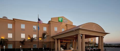 A Holiday Inn Express hotel with a clear entrance, flag, and palm trees.
