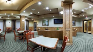 Classic hotel room with a dining table and chairs, television, and door to another room.