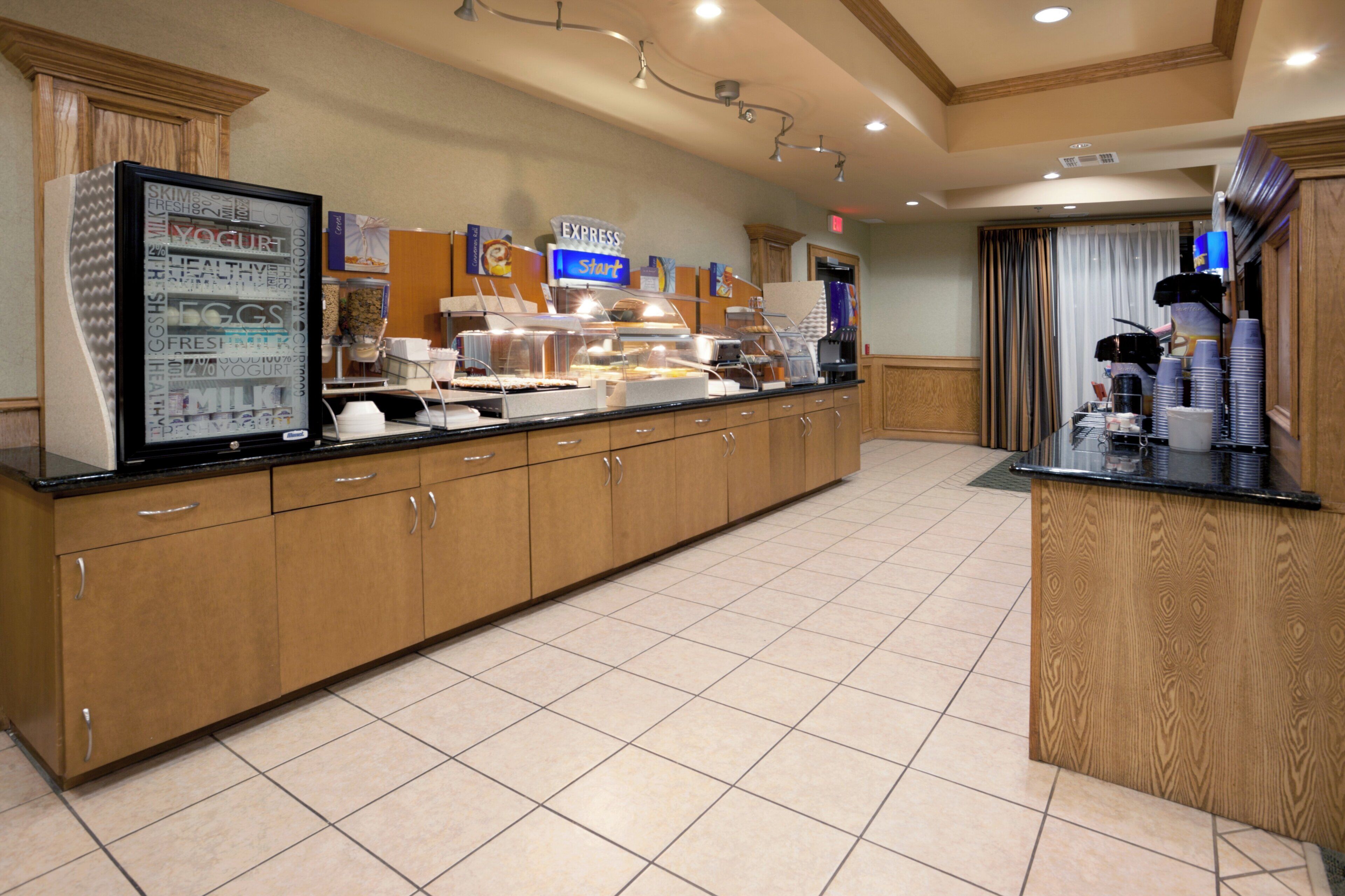 A buffet area with a refrigerated display case, a coffee station, and a variety of food items.